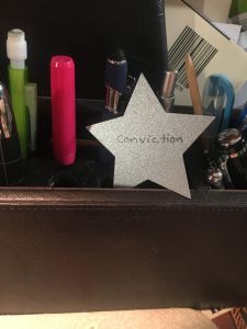 a photo of a desk organizer and a small star that says "conviction" on it.