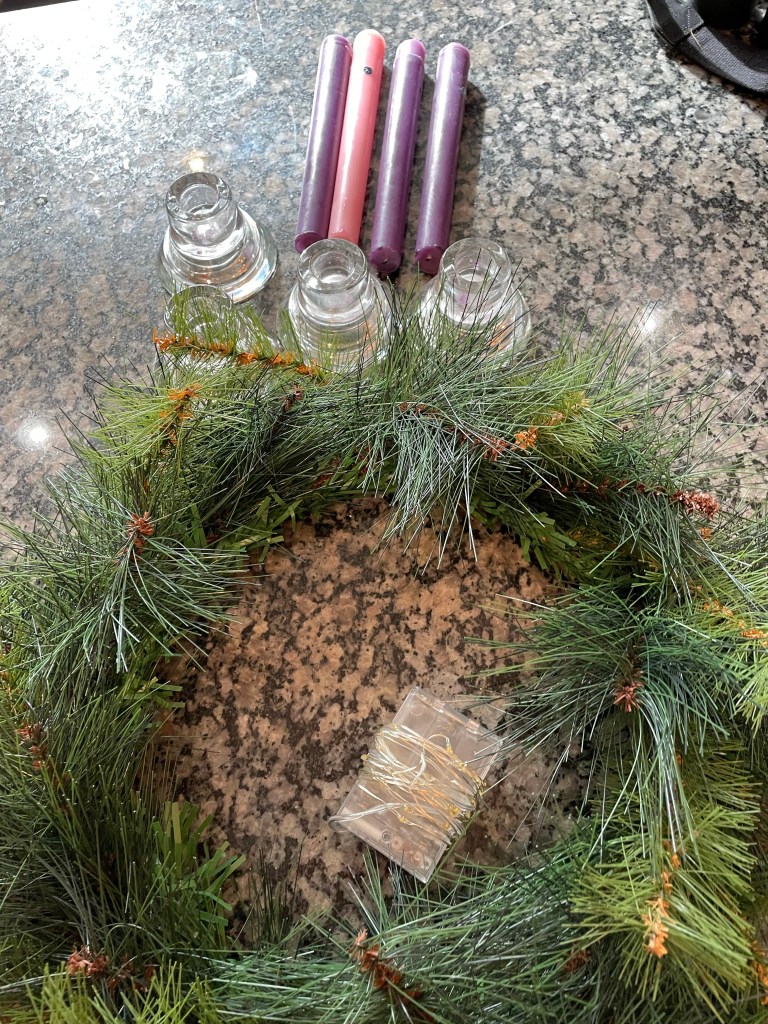 An Advent wreath deconstructed for storage… candles, wreath and lights.